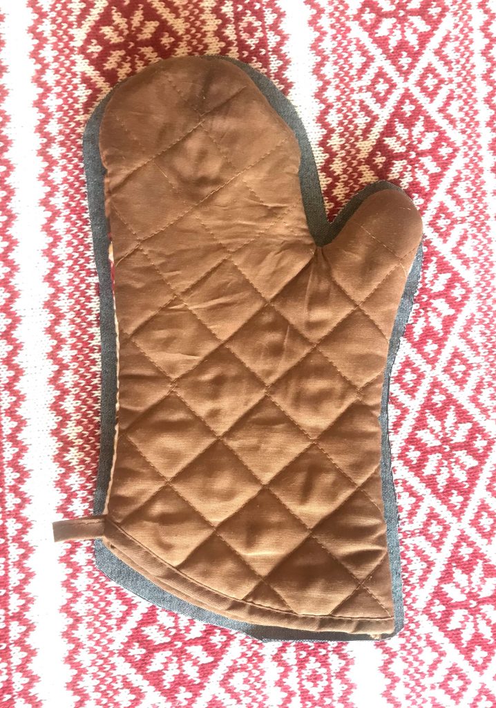 Brown guide Oven Mitt atop Fabric cut with 1/4 inch seam allowance around perimeter