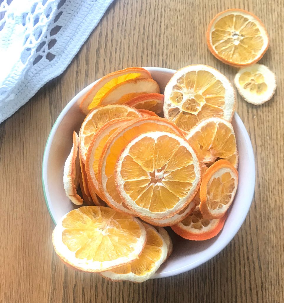 Bowl of dehydrated Oranges on a wooden table with a white table cloth