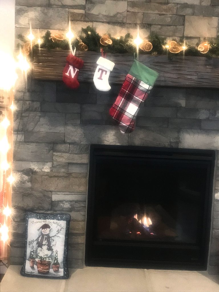 A fireplace with faux Christmas garland containing dehydrated Oranges 