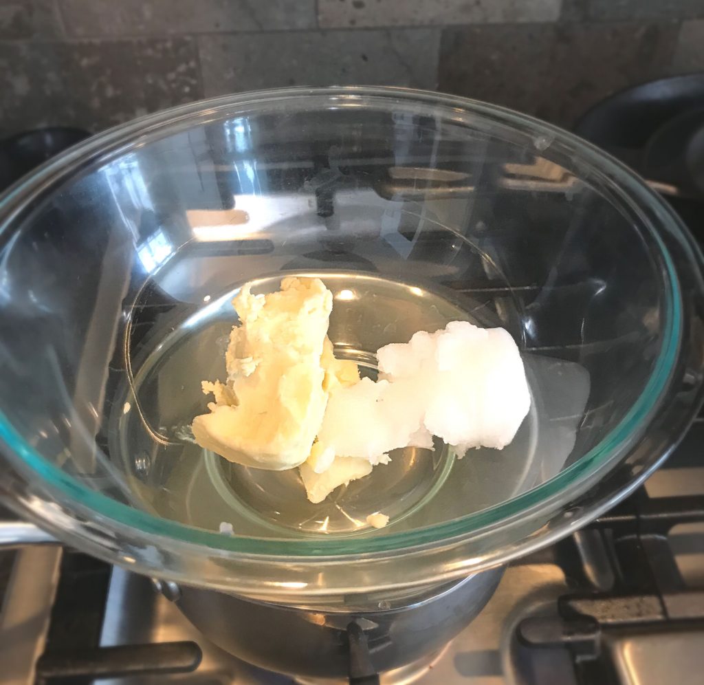 Shea butter and coconut oil in a glass bowl over a pot of water