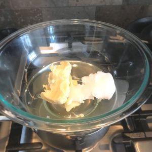 Shea butter and coconut oil in a glass bowl over a pot of water