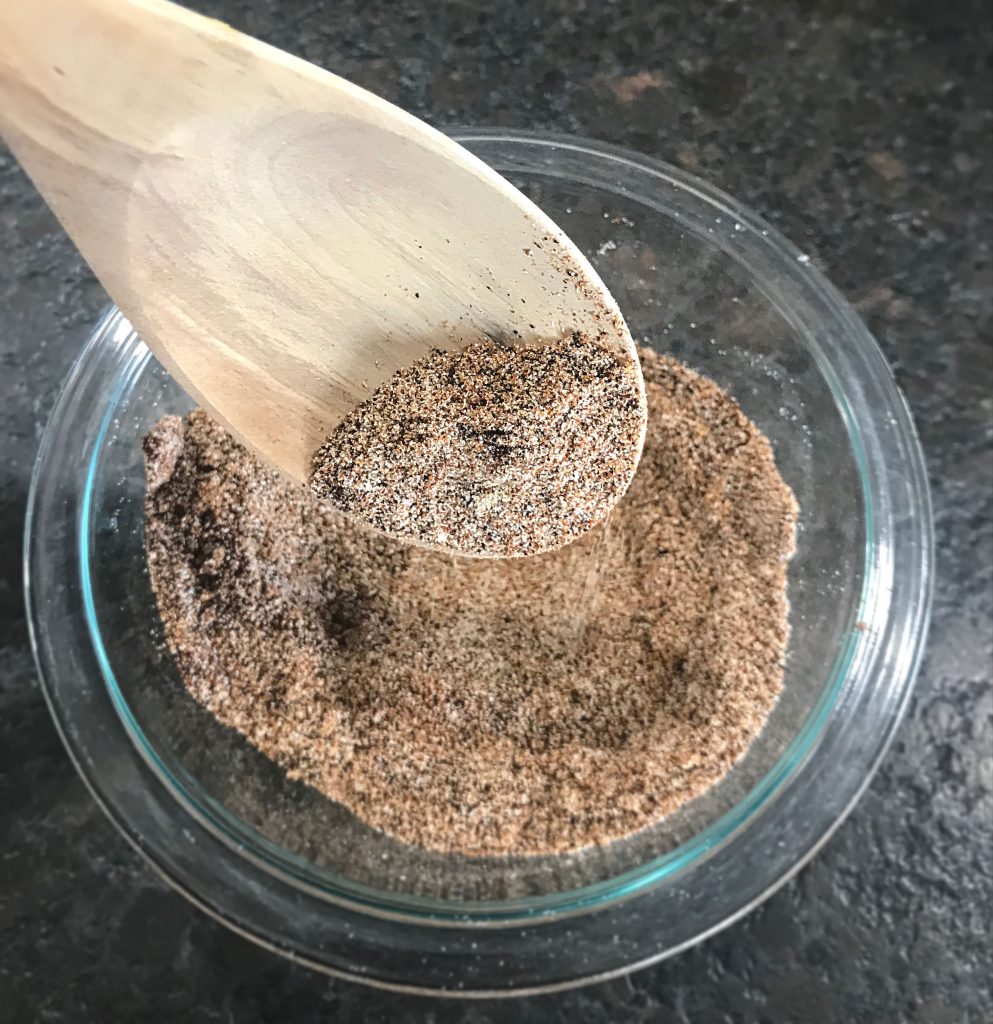 Taco Seasoning mixed and featured on a wooden spoon in a glass bowl