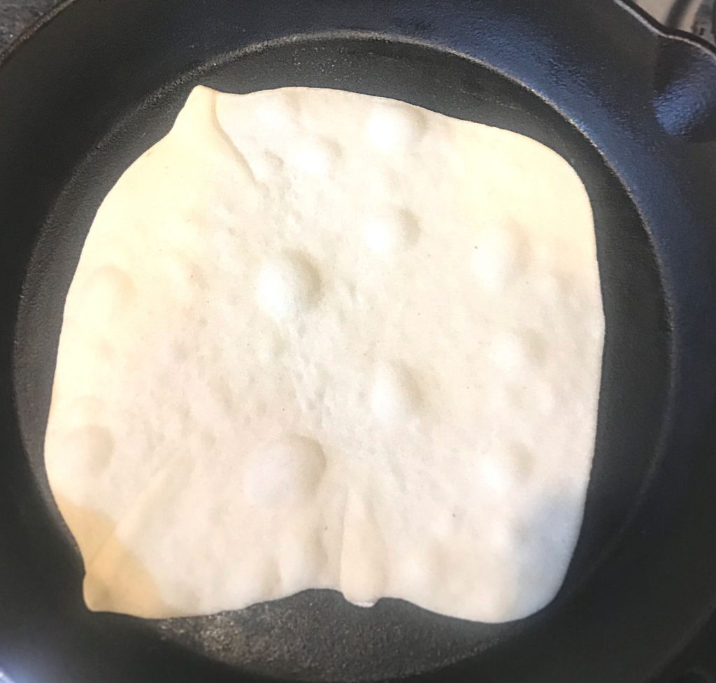 Tortilla cooking in a skillet that is ready to be flipped