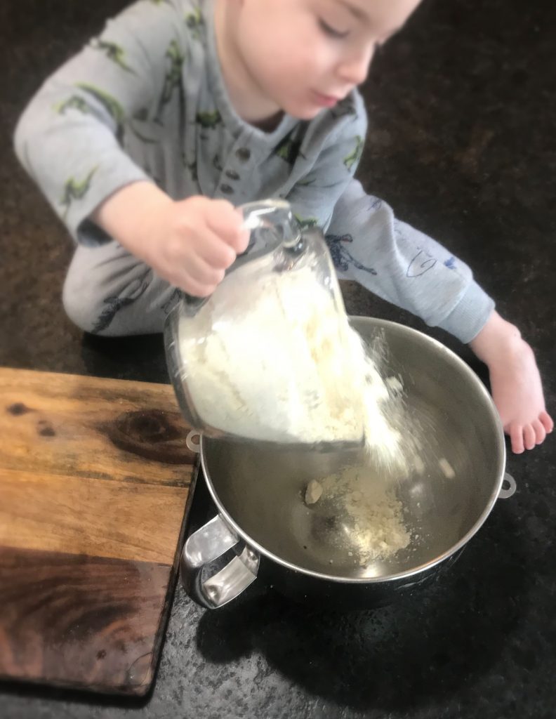Boy dumping All Purpose Einkorn flour into a bowl
