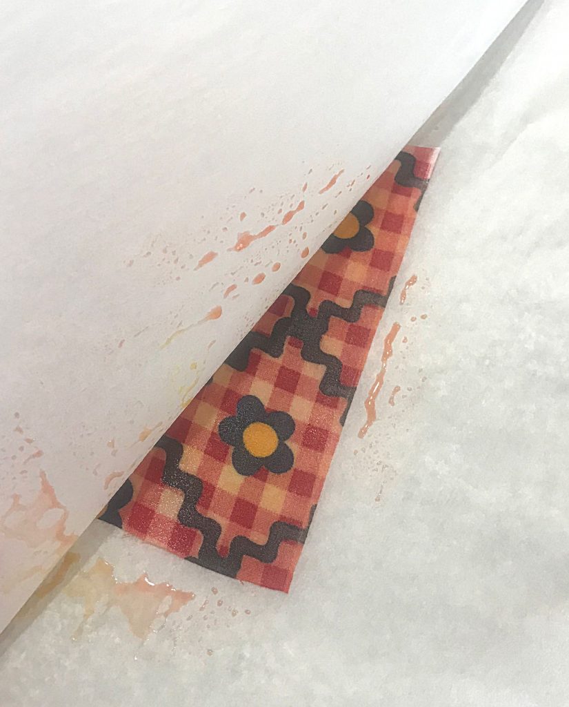 Beeswax melted onto a piece of red fabric with flowers on it