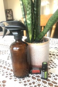 Amber glass spray bottle with doTERRA Essential Oils and a succulent on a white table cloth