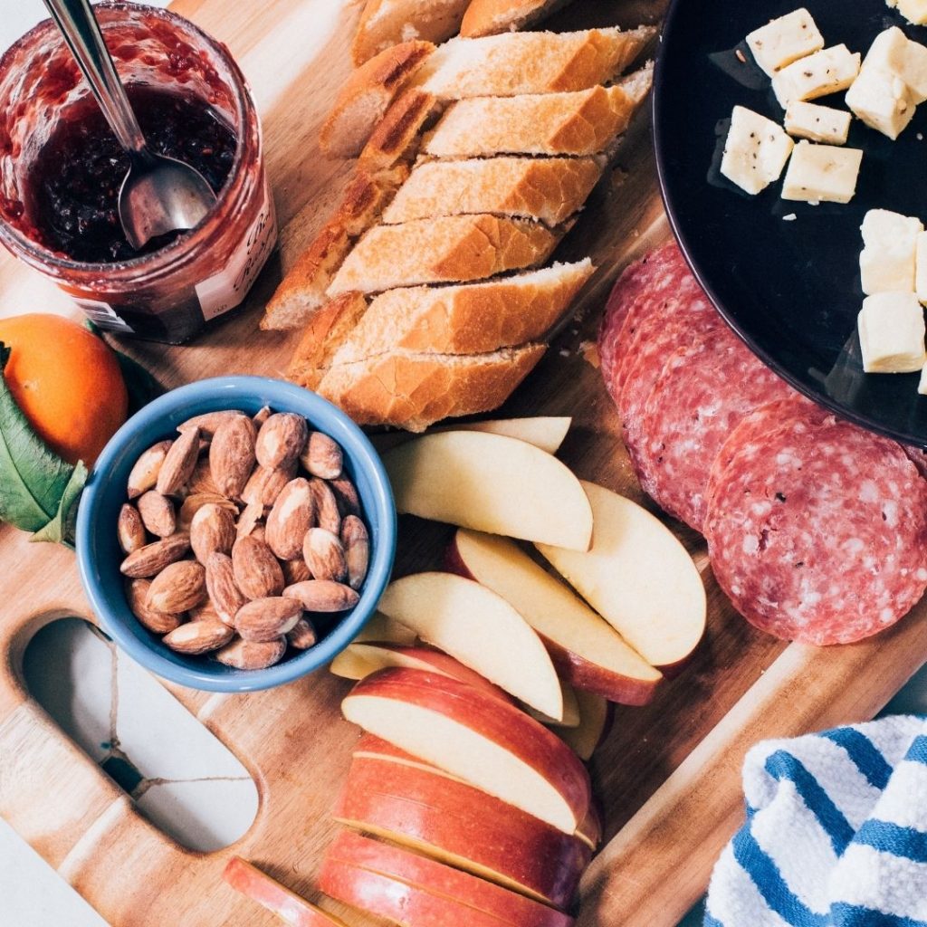 Salami, apples, nuts, and bread on a wooden board