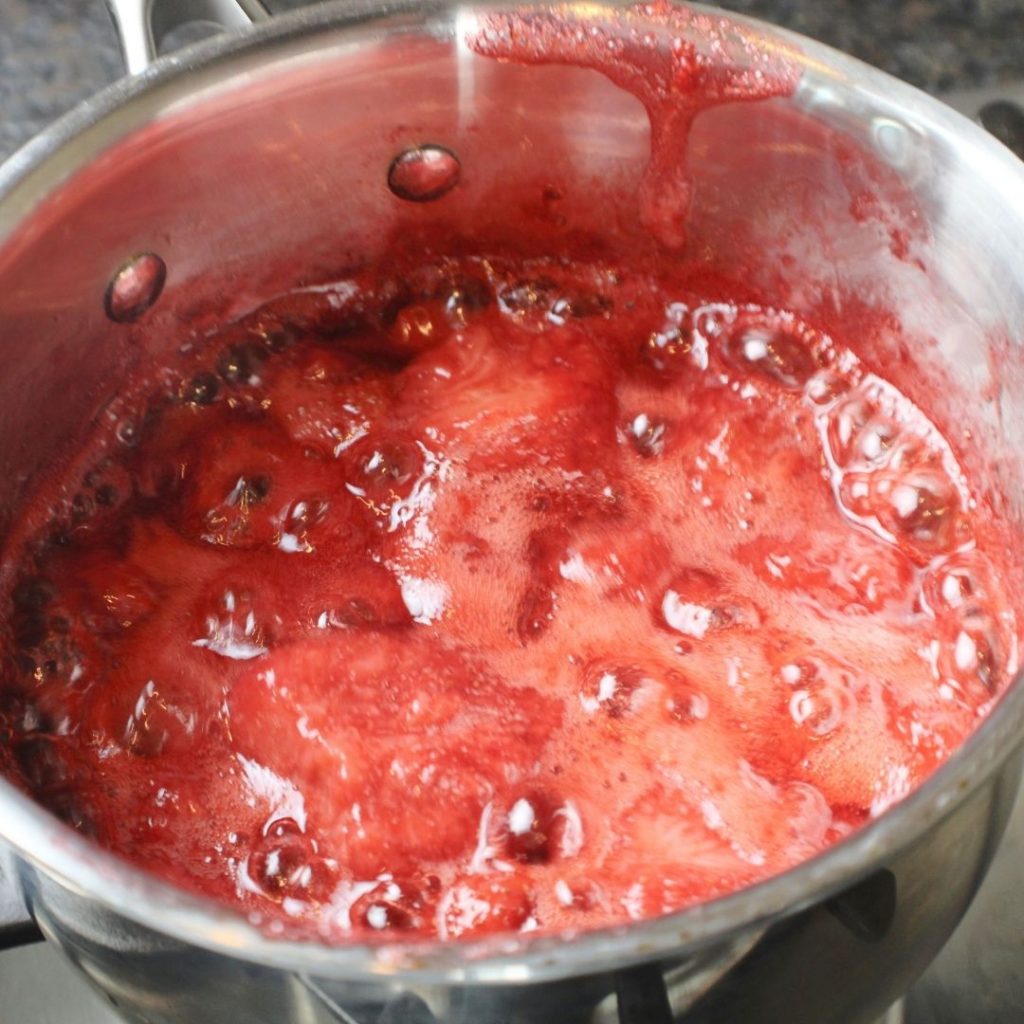 Strawberries and Honey cooked down to a jam in a saucepan.