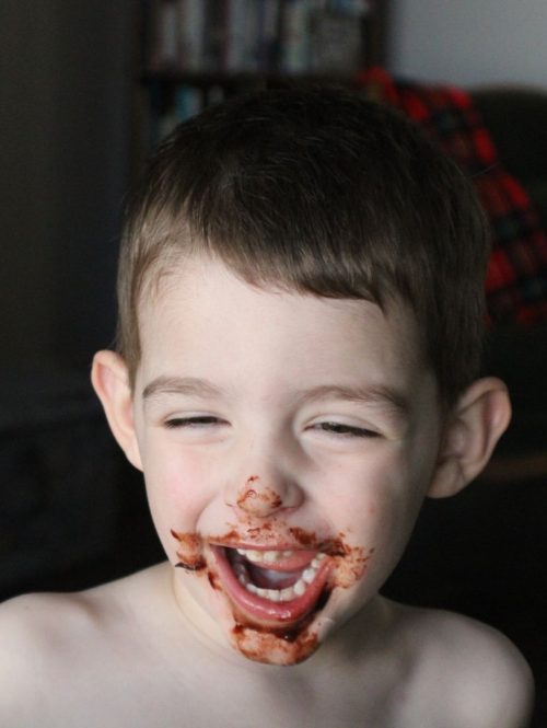 boy with chocolate brownie batter on his face and smiling