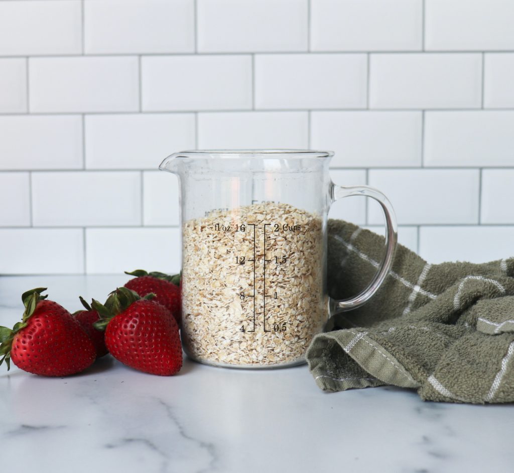 Oats in a pitcher next to Strawberries and a green towel