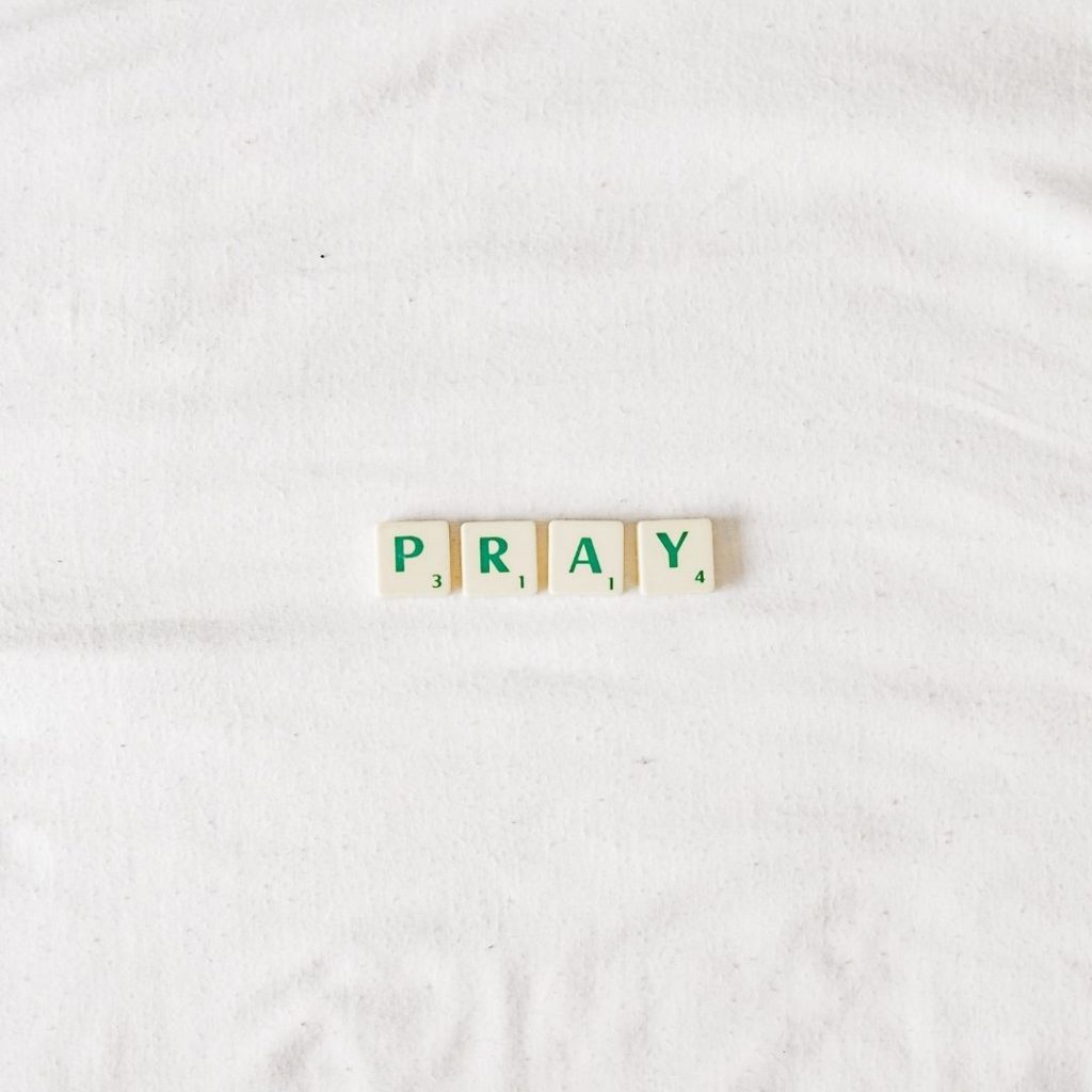 Scrabble letters spelling our PRAY on a white background