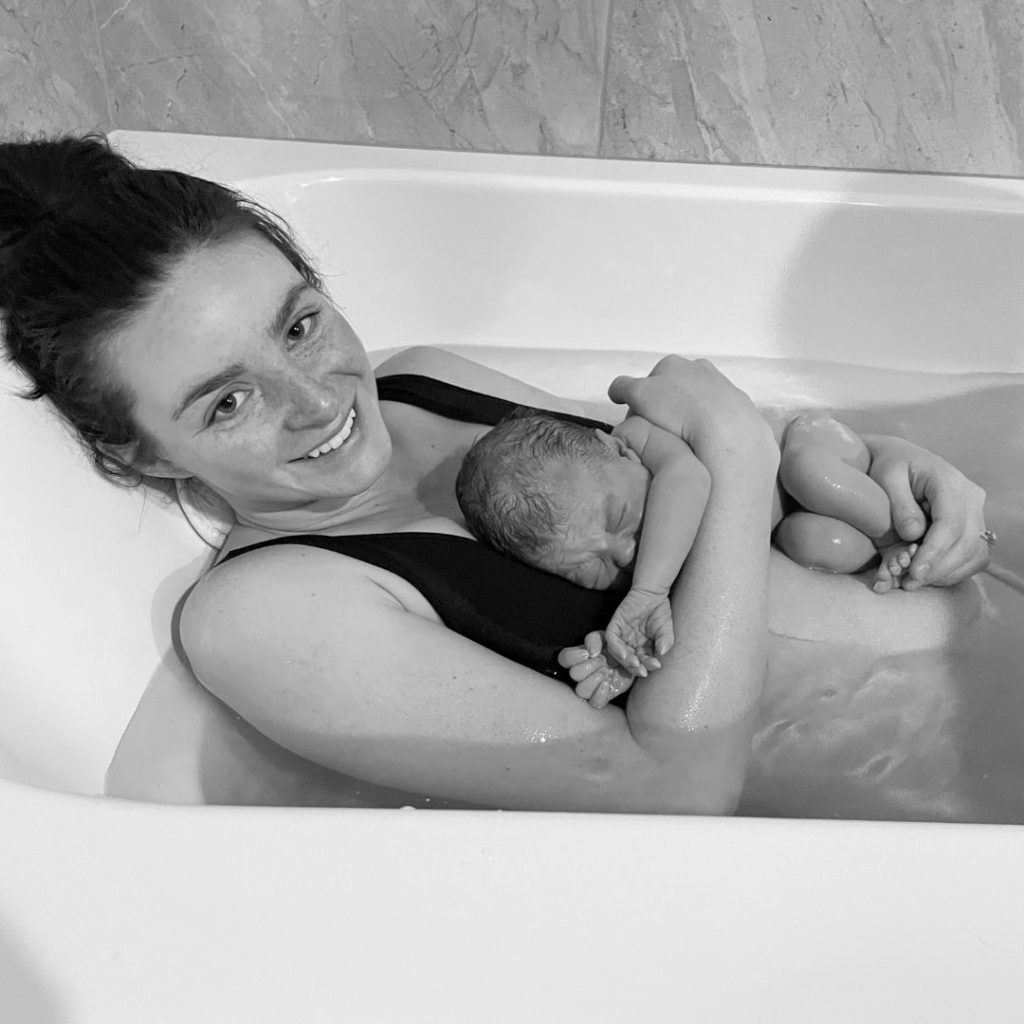 woman in a tub with her baby after birth